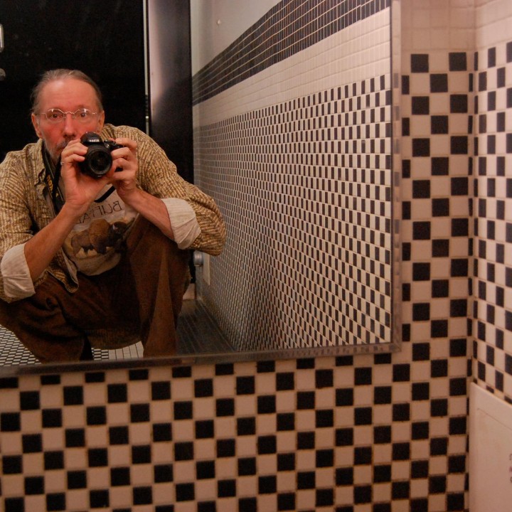 Photographer self-portrait in the mirror of a bathroom with checkered tiles