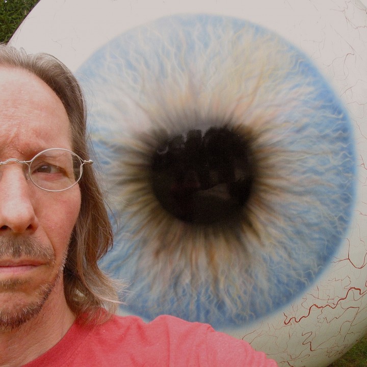 Giant eyeball outdoor sculpture with worried looking photographer