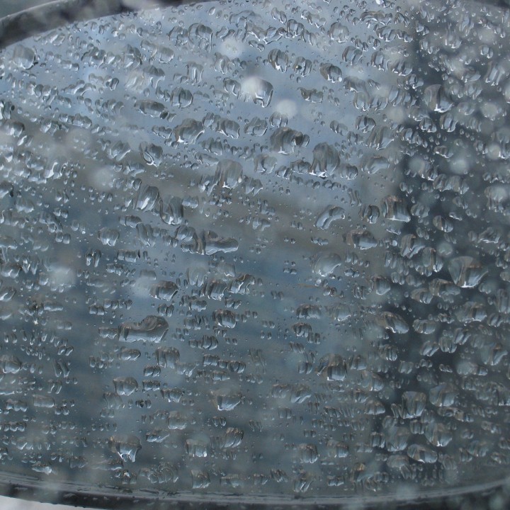 A drip-covered rear view mirror, seen through the driver's-side window
