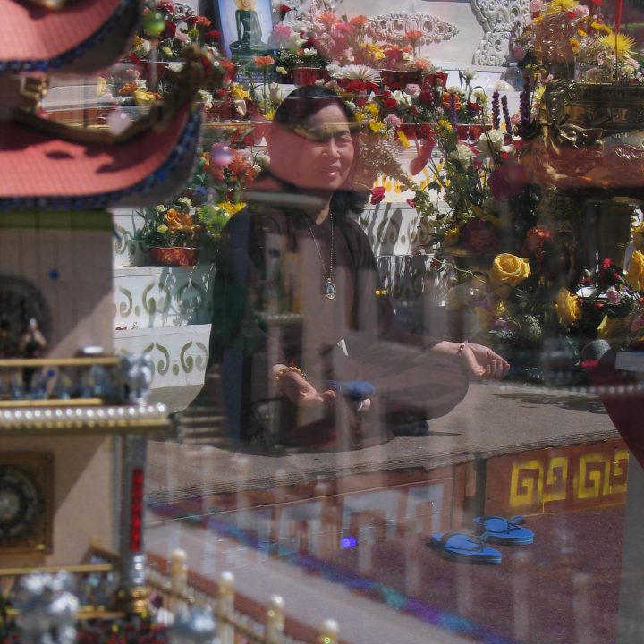 Woman in the lotus position, meditating in front of a shrine with various reflections in image