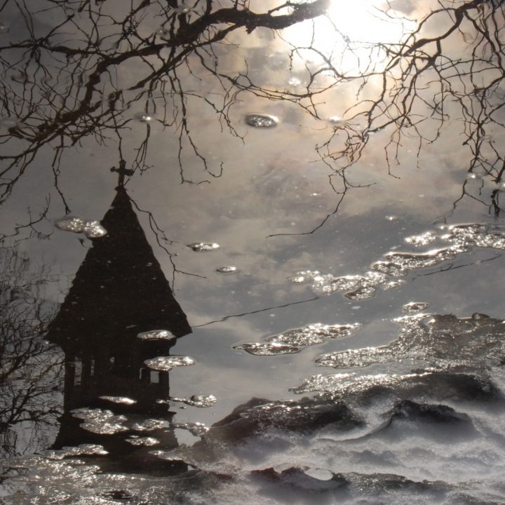 Steeple of All Saints Episcopal Church in Ravenswood neighborhood, reflected in snowmelt.