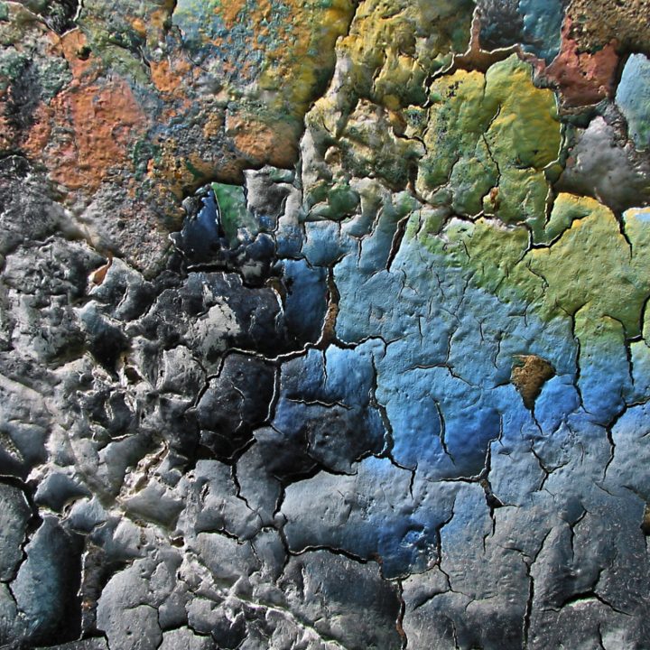 Abstracted layers of colorful decaying graffiti sidelit for dense texture